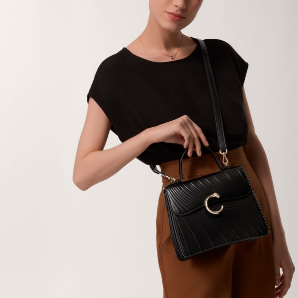 Handle bag mini model, Panthère de Cartier Black calfskin, embossed Cartier signature motif, golden finish